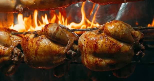Frangos dourados assando sobre a brasa